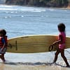 Two young children carry a surfboard to the water in Santa Catalina, Panama