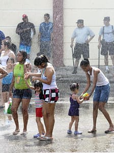 A Panamanian family cools off in the water spray along the Cinta Costera during the second day of Carnival 2012 in Panama