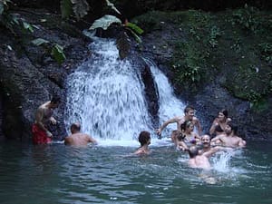 Tour members enjoy splashing in this waterfall during the Panama Canal Kayak Tour